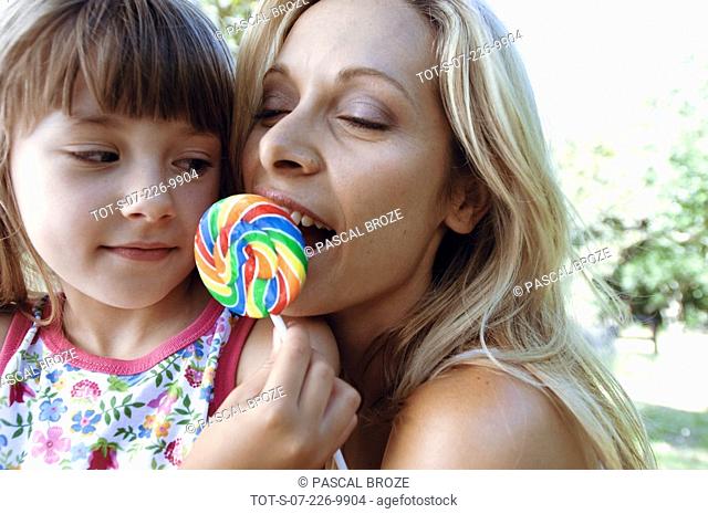 Close-up of a girl feeding lollipop to her mother