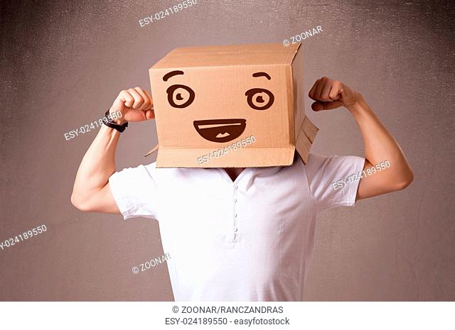 Young man gesturing with a cardboard box on his head with smiley face