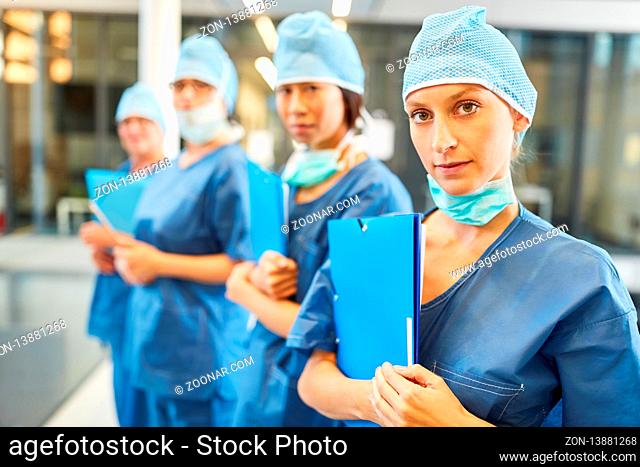 Junge Ärztin in blauer OP-Kleidung zusammen mit Kollegen als Chirurgie Team