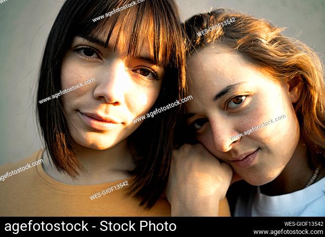 Young lesbian couple leaning on each other during sunset