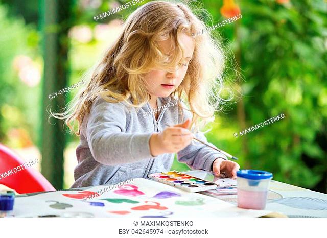 Portrait of little blonde girl painting, summer outdoor