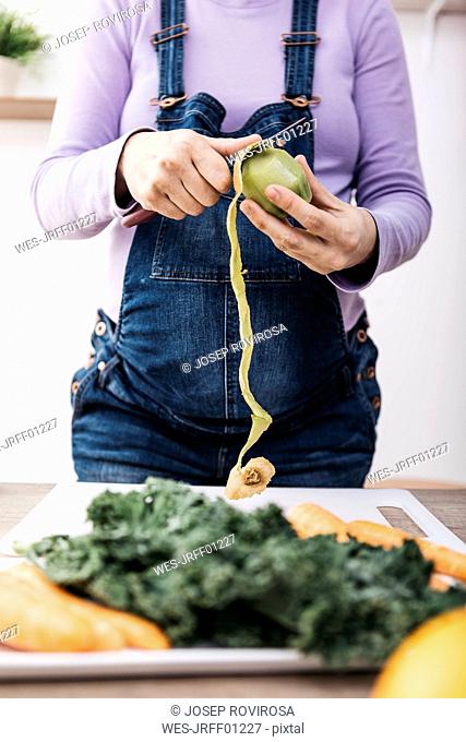 Woman peeling kiwi for preparing fruit smoothie, partial view