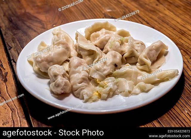 Plate of ready freshly cooked dumplings made during chinese dumpling making and cooking class in a travelers hostel, Chengdu, Sichuan Province, China
