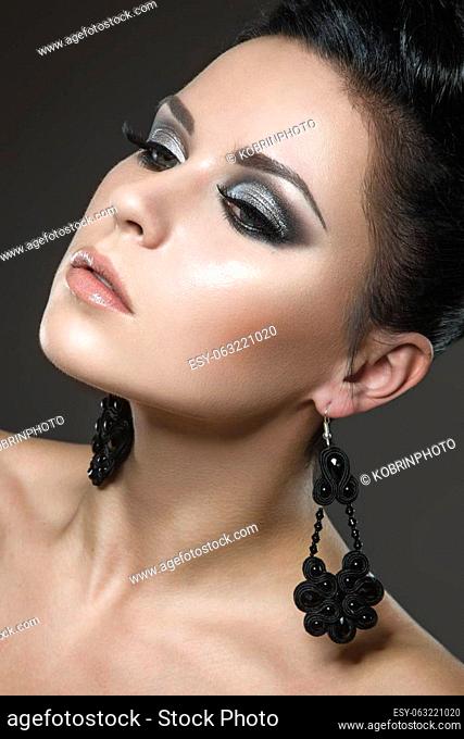 Beautiful brunette woman with perfect skin and handmade jewelry. Picture taken in the studio on a black background