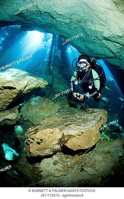 Mario, a cavern/cave guide with Dive Adventuras, dives near the stricking sunlight rays visible during a dive in Chac Mool (God of Rain) Cenote, Riviera Maya