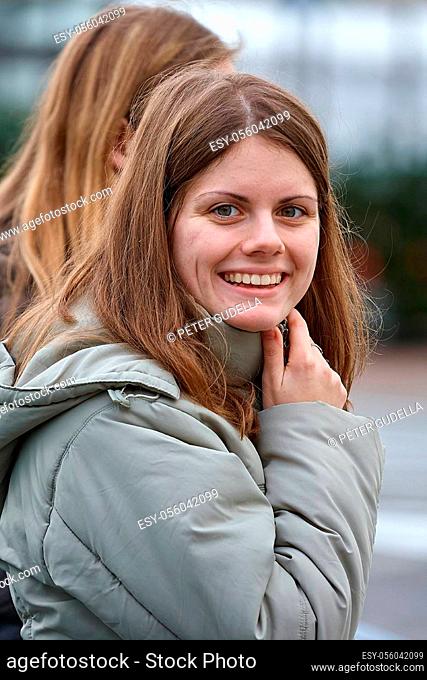 Woman walking on a street turning towards camera and smiling