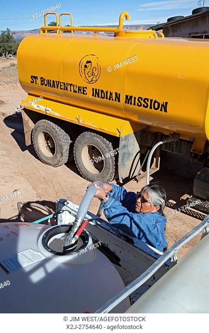 Thoreau, New Mexico - Darlene Arviso of St. Bonaventure Indian Mission fills a water tank for a Navajo family. One-third of the Navajo Nation's families lack a...