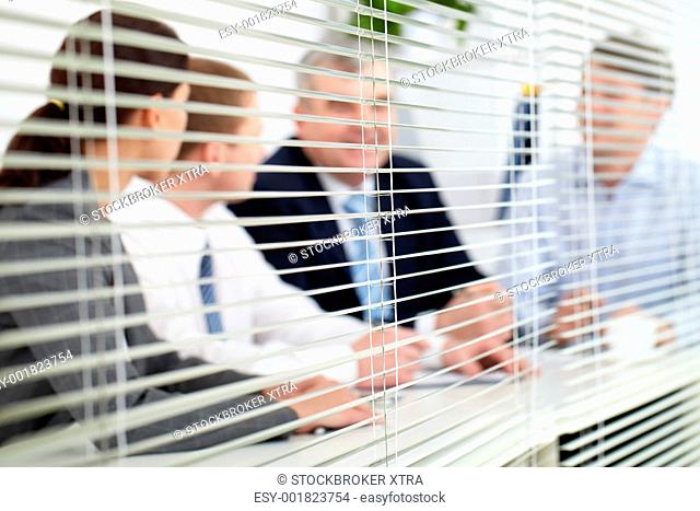 Business team sitting behind blinds
