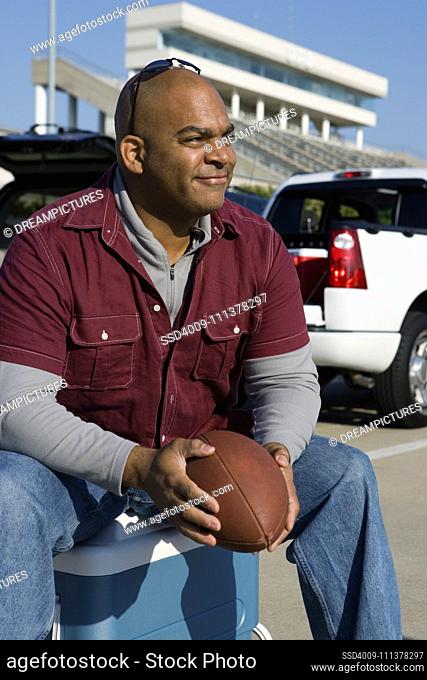 African man holding football at tailgate party