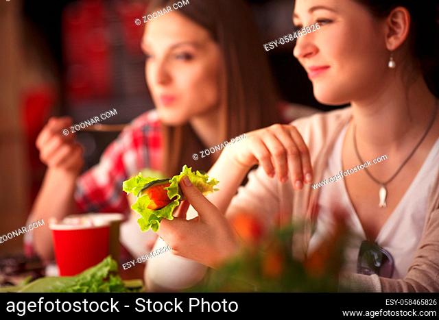 Closeup toned image of happy lady holding vegetarian dish and smiling. Beautiful women spending free time in cafe or restaurant