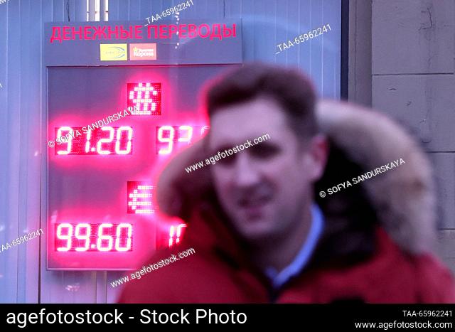 RUSSIA, MOSCOW - DECEMBER 21, 2023: A man walks past an information board showing foreign currency exchange rates. The Bank of Russia has set the US dollar rate...