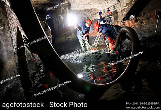 14 January 2021, Hamburg: Sewer workers use shovels and suction hoses to clean the strainer junction structure at the Hafenstraße pumping station