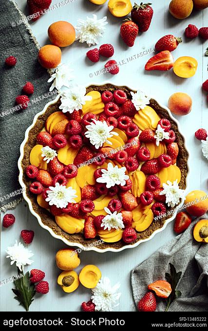Fruit tart with apricots and raspberries decorated with flowers