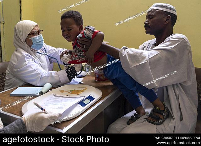 04 May 2023, Egypt, 6th of October City: A picture made available on 8 May 2023 shows a doctor from the Egyptian Red Crescent Society examining a Sudanese child...