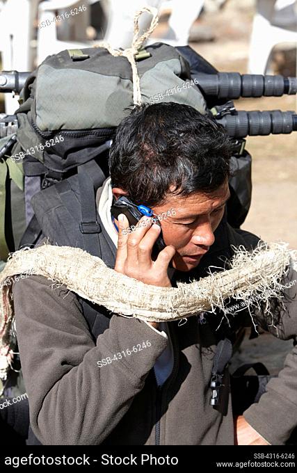 Nepal, Khumbu Region, Himalaya, close-up of Nepalese Sherpa porter talking on mobile phone