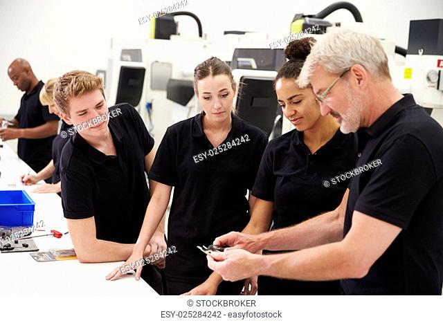 Engineer In Factory With Apprentices Checking Components