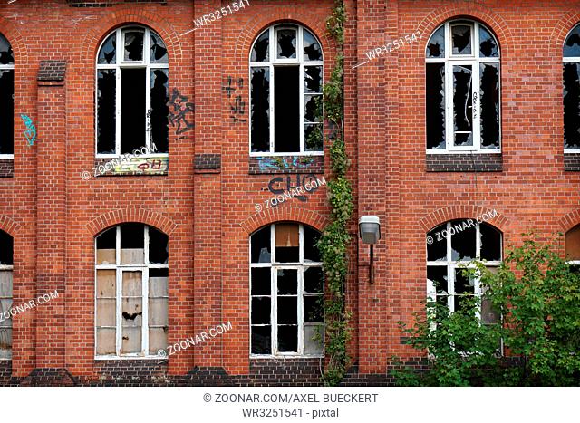 derelict red brick facade with broken windows