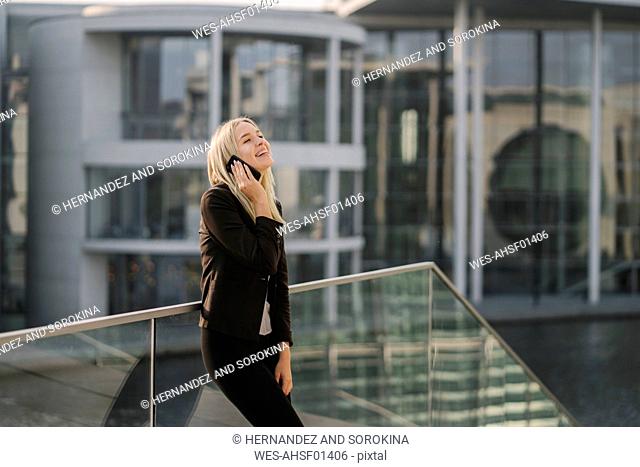Blond businesswoman using smartphone in the background modern building
