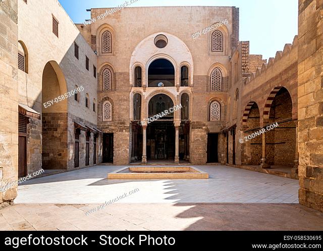 Main Iwan at courtyard of public historic mosque of Sultan Qalawun with huge arches, wooden doors and decorated windows, Cairo, Egypt