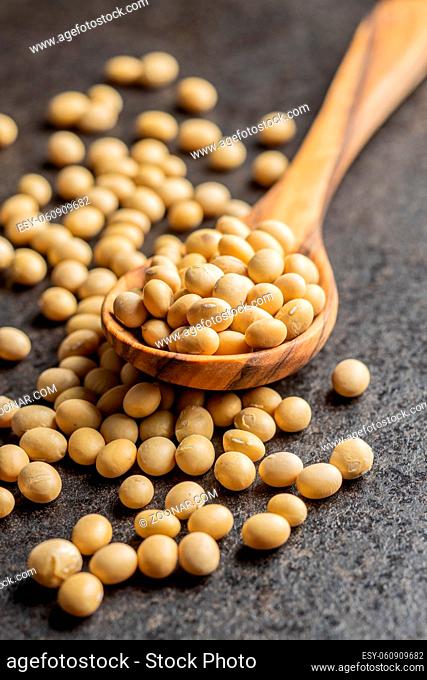 Dried soy beans in wooden spoon on a black table