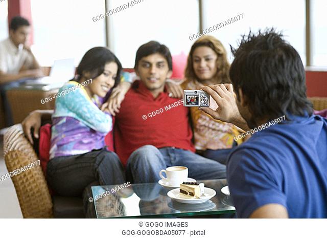 Man taking picture of friends in cafe