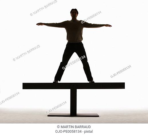 Man standing on a plank with arms out