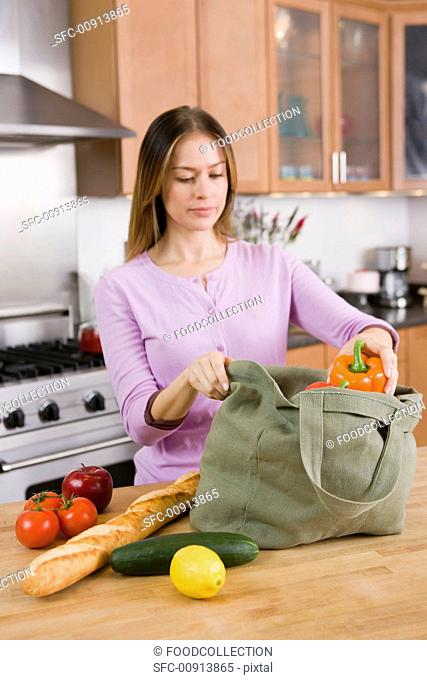 Woman Unloading Groceries from Cloth Bag on Kitchen Counter