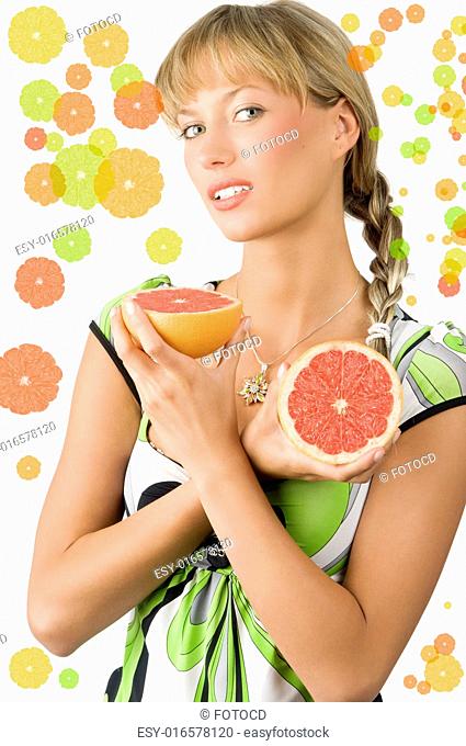 blond and cute girl with green dress and hair braid showing half grapefruit