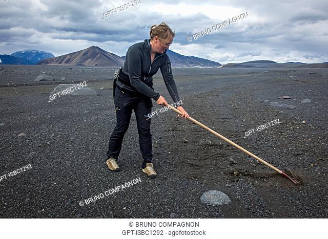 YOUNG WOMAN RESTORING F 910 WORN BY 4X4 VEHICLES, TRAIL LEADING TO THE VOLCANO ASKJA AND THE KVERKFJOLL MOUNTAIN, VOLCANIC DESERT AND LAVA FIELD