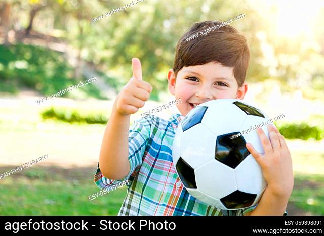 Cute Young Boy Playing with Soccer Ball and Thumbs Up Outdoors in the Park