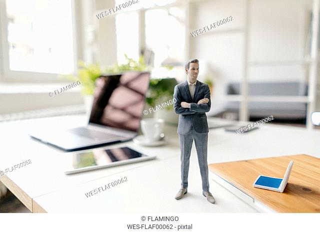 Businessman figurine standing on a desk with mobile devices