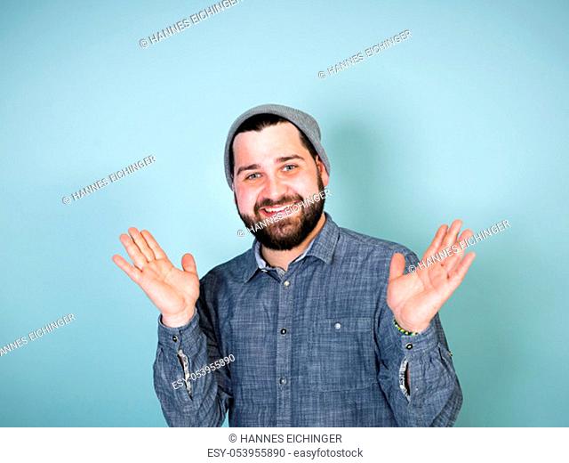 cool and young man with grey hood posing in front of blue background doing different body exprssions with copy space and is happy