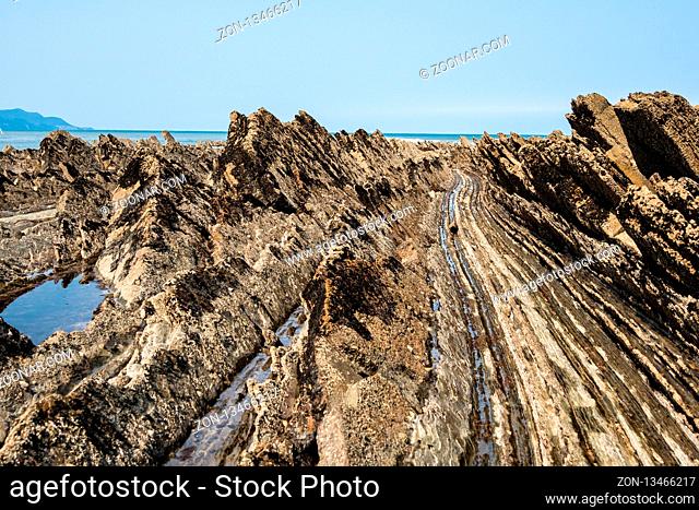 Flysch Coast of Sakoneta, Zumaia, Spain. Flysch is a sequence of sedimentary rock layers that progress from deep-water and turbidity flow deposits to...