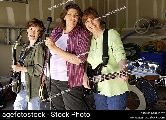 Portrait of Garage band composed of middle aged women with instruments, practicing in residential garage