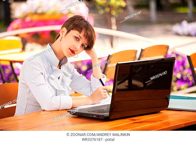Young fashion business woman using laptop at sidewalk cafe