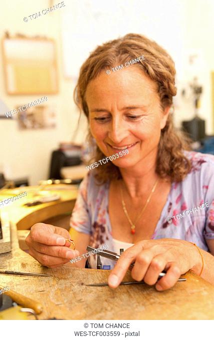 Germany, Bavaria, Munich, Mature woman working on ring in her workroom at home