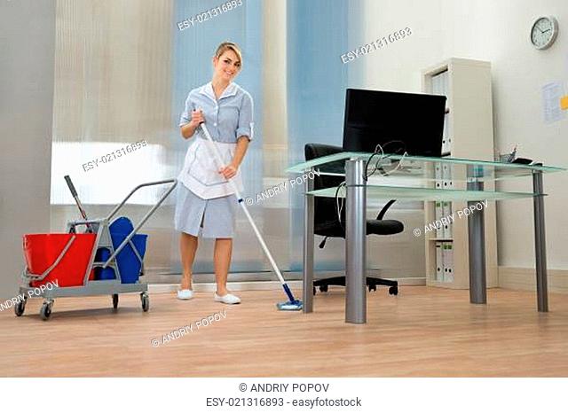 Young Happy Female Maid Cleaning Floor In Office