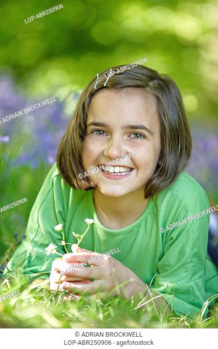 England, Buckinghamshire, Stokenchurch, A happy young girl lying in a wood full of Bluebells