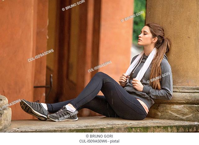 Young woman wearing sports clothes sitting resting