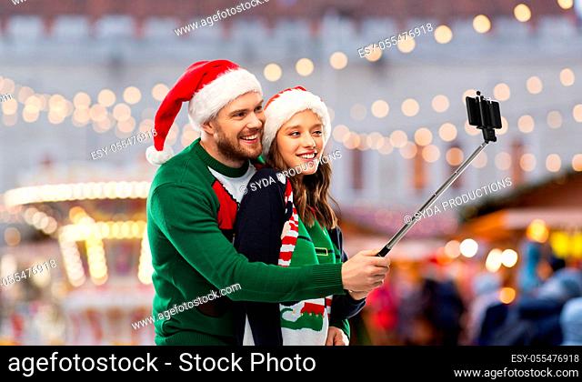 happy couple in christmas sweaters taking selfie