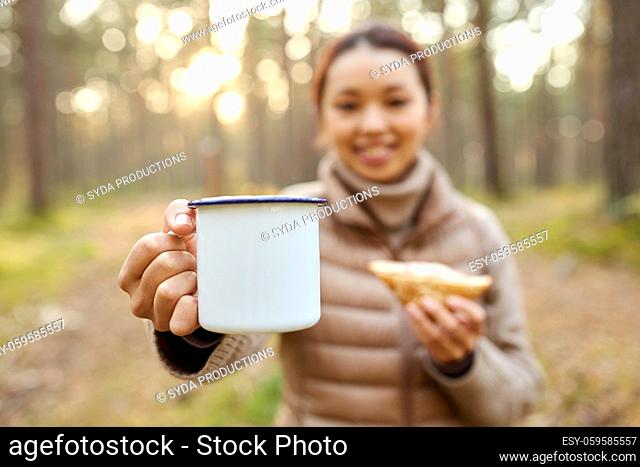 asian woman with mug drinking tea in forest