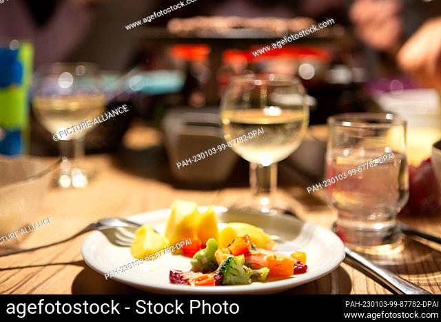 PRODUCTION - 31 December 2022, North Rhine-Westphalia, Bergheim: During a raclette meal on New Year's Eve, vegetables topped with cheese lie on a plate