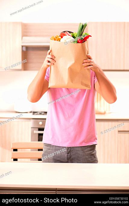 Young handsome man with vegetables in the kitchen