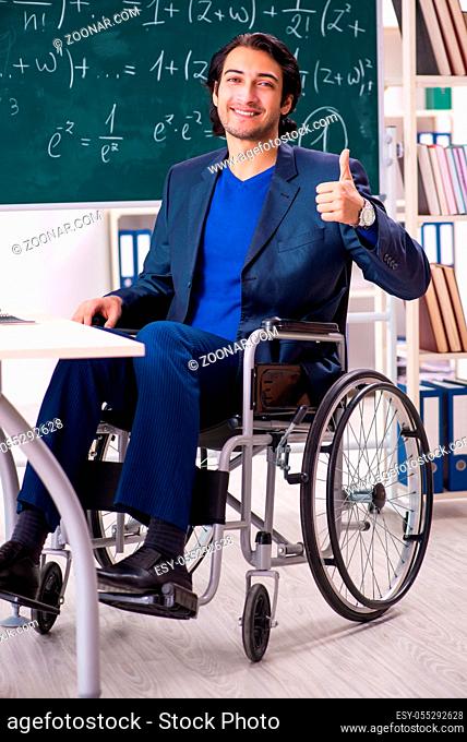 Young handsome man in wheelchair in front of chalkboard