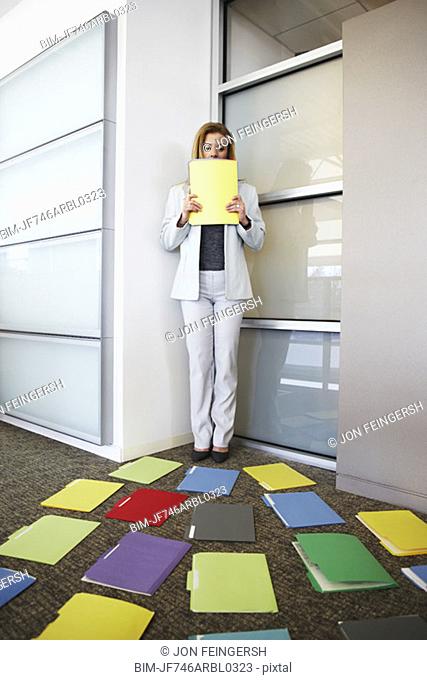 Businesswoman backed into corner by file folders