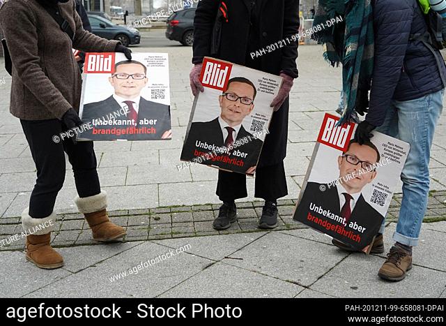 11 December 2020, Berlin: Climate activists hold photos of Mario Mehren, Chairman of the Board of Executive Directors of the gas and oil producer Wintershall...