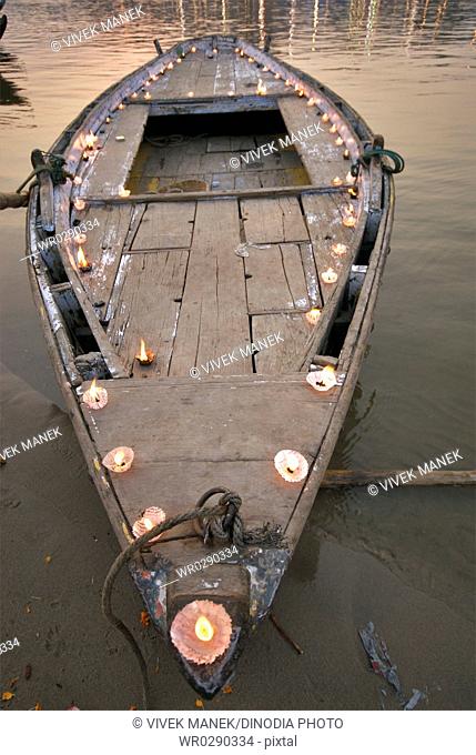 Lamps or diyas lighted on boat at banks of holy Ganga river , Varanasi , Uttar Pradesh , India