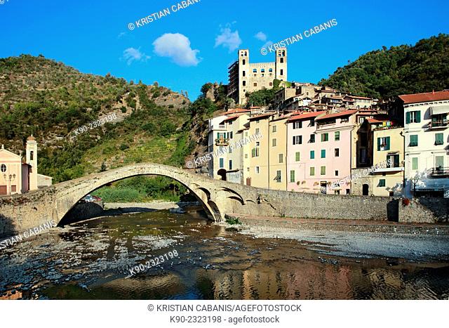 Stone bridge Ponte Vecchio across the Nervia river with residential buildings and the remains of the old fortress Castello dei Doria and church, Dolceacqua