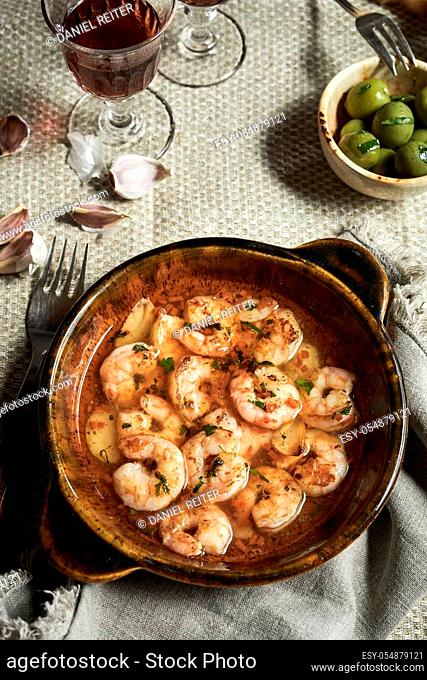 Dish of gourmet Spanish scampi sauteed with garlic and seasoned with herbs and spices viewed from above on a rustic table