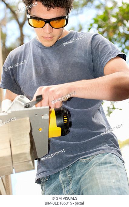 Hispanic man using saw
